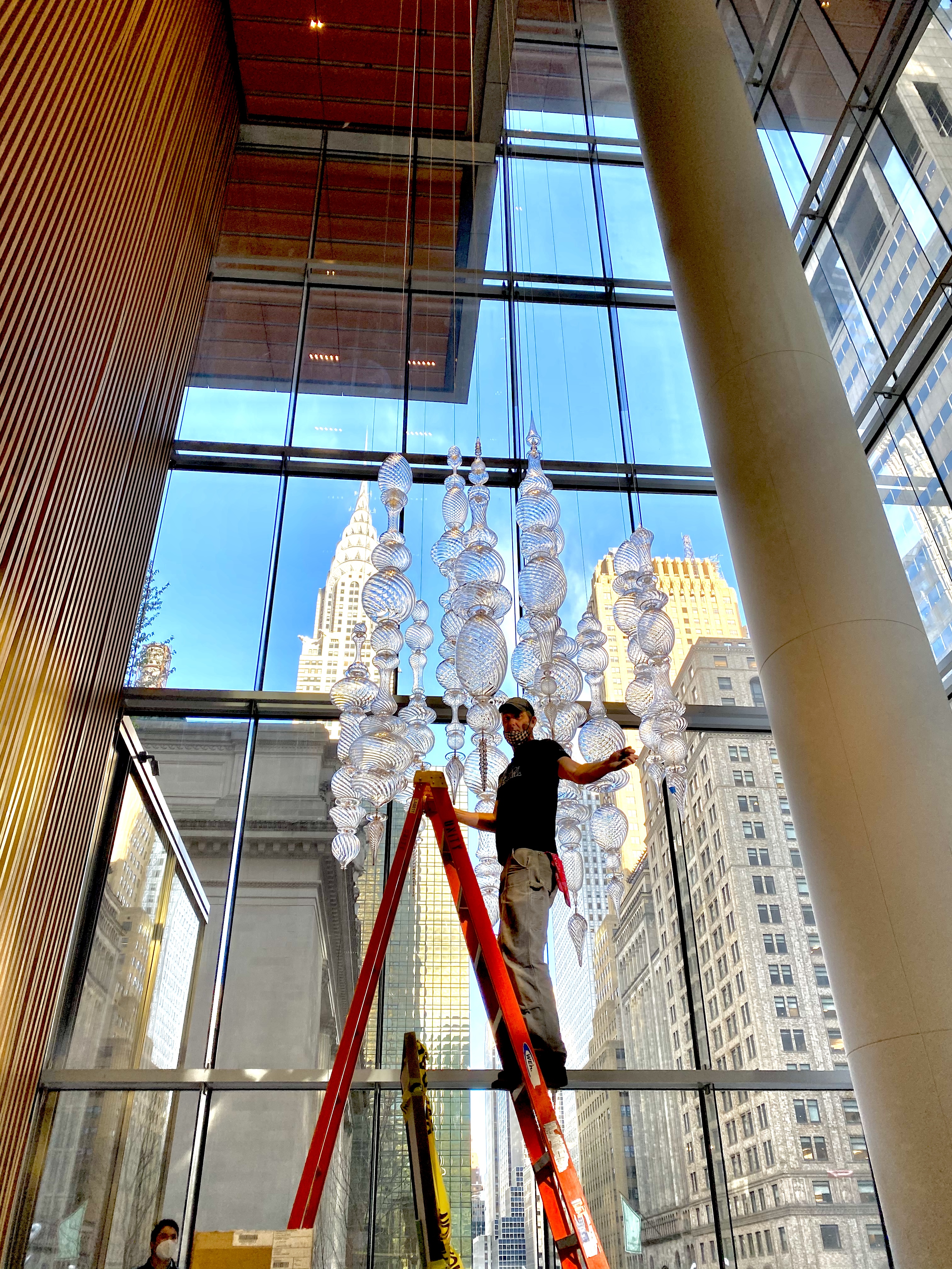 Andy Paiko on a ladder next to his Le Pavillion chandelier