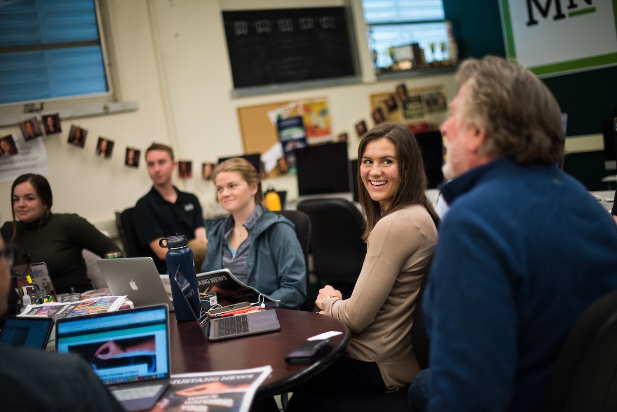 Journalism students and professors gathered at a table