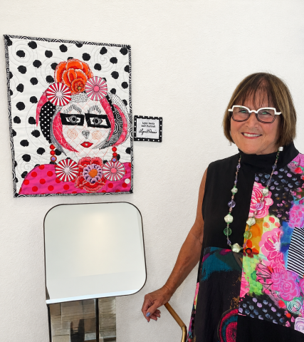 Lynn Davis poses next to one of the works from. her first art show