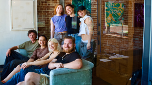 Art and Design students smile looking at the camera in an art gallery