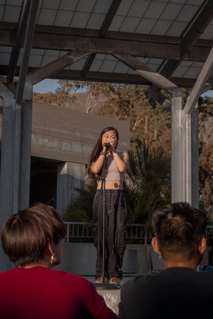 Ruby Ibarra, wearing a tan crop top and dark baggy pants, holding the microphone and singing on the University Union Stage