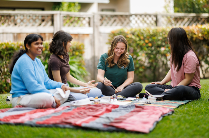 Group of students smiling and painting in a park. 