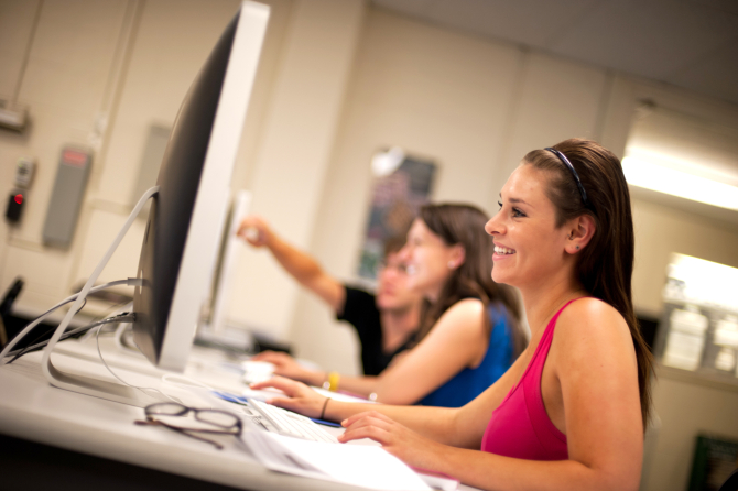 Student working on a computer and smiling. 