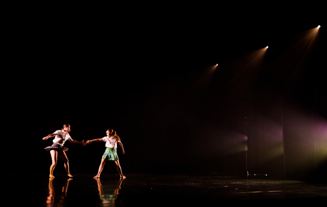 Two students performing in a dark theater stage