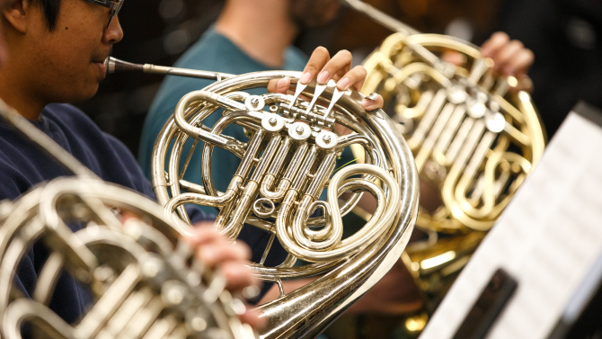 Student playing the french horn for the cal poly symphony