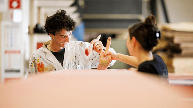 Two students with paintbrushes work on producing the set for their winter production of Clue: The Musical.
