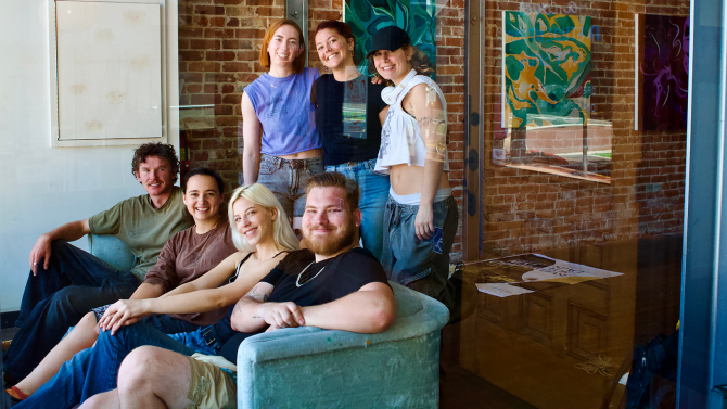 Art and Design students smile looking at the camera in an art gallery