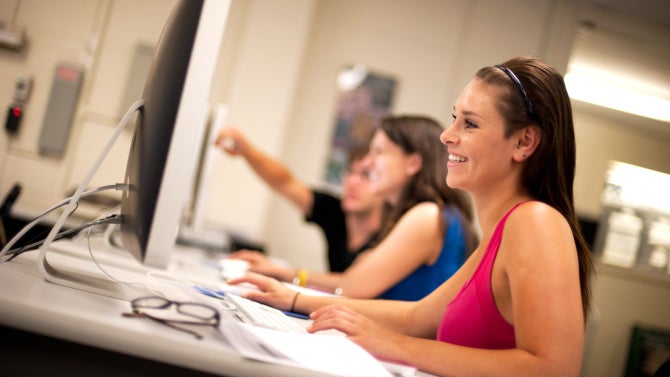 Student working on a computer and smiling. 
