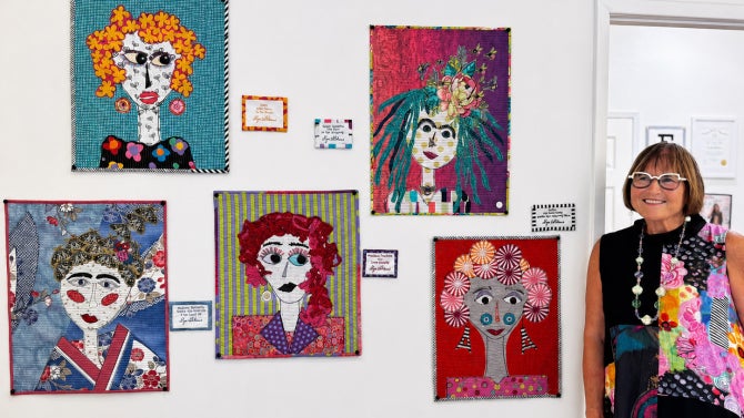 Lynn Davis poses next to artwork on a white wall